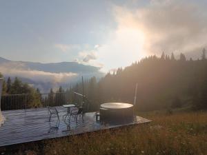 a wooden deck with a grill and chairs on a table at Motyl Glamping Resort in Dzembronya +2 photos