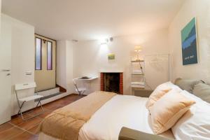 a bedroom with a white bed and a fireplace at Lilliput Tiny Studio in Bellagio