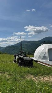 a jeep parked next to a tent in a field at Motyl Glamping Resort in Dzembronya