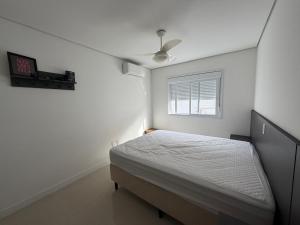 a white bedroom with a bed and a window at Ed. Mauí, 2 suítes, divisa Capão e Atlântida in Capão da Canoa +20 photos