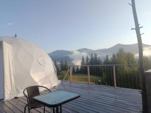 a wooden deck with a table and a chair on it at Motyl Glamping Resort in Dzembronya