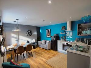a kitchen and living room with blue walls and a table at Spacious 2BR with garden in Alnwick
