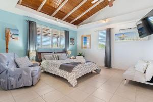 a bedroom with a bed and a couch and a tv at Gaviota del Mar with private pool in Rincon