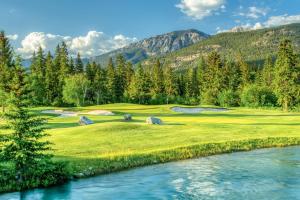 a golf course in the mountains next to a river at Cozy getaway with a view! in Fairmont Hot Springs