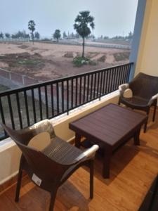a balcony with two chairs and a table and a view of a field at Aarna Beach Stay in Vadarevu