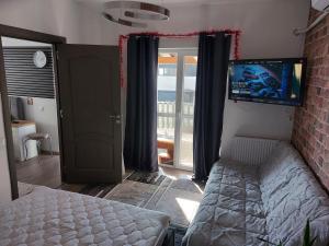 a bedroom with a bed and a tv and a door at Casa Capibarei 3 in Bragadiru