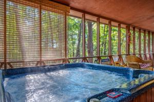 a jacuzzi tub in a room with windows at Fox Hollow - Hot Tub, Wifi, Pet Friendly, Screen Porch, Deck, Recreation Center, Pool Access, Golf Nearby, Hiking, Grill, Fireplace, King Bed in Hedgesville