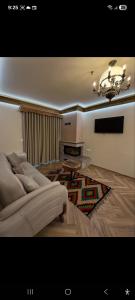 a living room with a couch and a chandelier at Hotel Restorant Unaza in Voskopojë