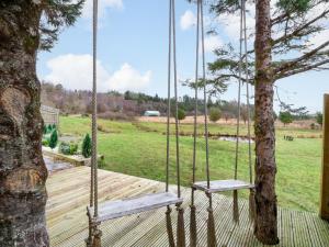a swinging porch with a tree and a field at Crofters Suite in Acharacle
