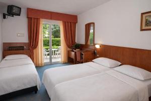 a hotel room with two beds and a balcony at Hotel Garden Limone in Limone sul Garda