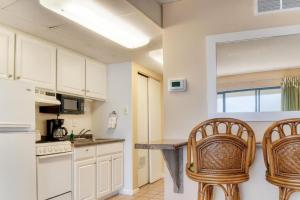 two chairs in a kitchen with white cabinets and a counter at Boardwalk One- Studio w Balcony and Partial Ocean View in Ocean City