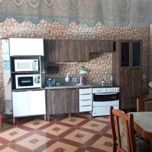 a kitchen with white appliances and a tile floor at Aluguel Nova Tramandaí in Tramandaí