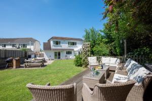 a patio with wicker chairs and a table and a house at 5 Bed in Croyde oc-brambc in Croyde