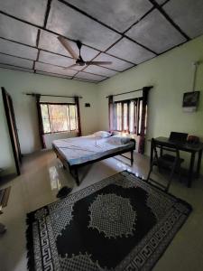 a room with a bed and a table and a rug at Commander's Home in Kangra