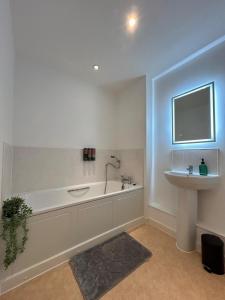 a bathroom with a bath tub and a sink at Central Hemel 2-Bed Flat with Secure Parking in Hemel Hempstead +12 photos