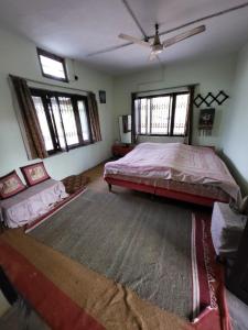 a bedroom with a large bed and windows at Commander's Home in Kangra