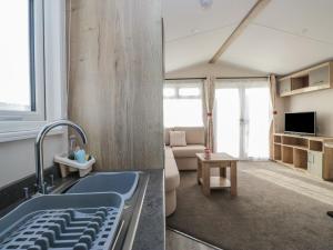 a kitchen with a sink and a living room at Guillemot in St Bees