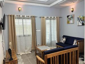 a living room with a blue couch and windows at Velo Apartments in Kribi in Kribi