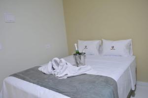 a white bed with a bucket of toothbrushes on it at Flat Ubarana Maragogi-AL in Maragogi