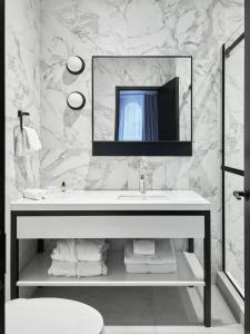 a white bathroom with a sink and a mirror at Le Petit Hotel Notre Dame in Montreal