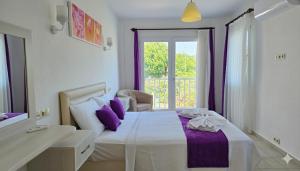 a bedroom with a bed with purple pillows and a window at Dalyan Villa Amazon in Dalyan