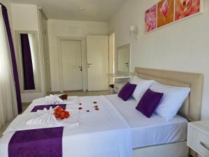 a white bed with purple pillows and flowers on it at Dalyan Villa Amazon in Dalyan +34 photos