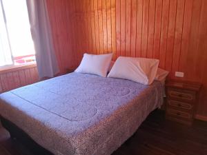 a bedroom with a bed with two pillows and a window at Mini departamento 3 in Coñaripe