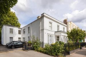 a white house with a car parked in front of it at Maitland House Boutique Apartment in Gloucestershire