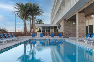 a swimming pool with blue chairs and a building at Hotel Eastport in The Villages
