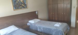 a bedroom with two beds and a wooden headboard at Cyro Palace Hotel Ltda in Caçapava do Sul