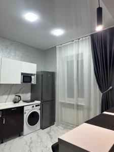 a small kitchen with a refrigerator and a microwave at Apartments Velora in Kryvyi Rih +4 photos