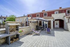 a patio with a table and chairs and an umbrella at Casa Maja in Brtonigla