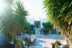 a backyard with a table and chairs and palm trees at Merovigli Suites in Mérikhas