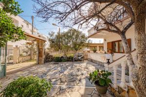 a house with a tree and a stone patio at Garden Villa Dhesara in Ksamil