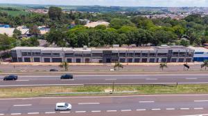 a large building with cars parked in front of a road at Jahu Center Plaza Flats in Jaú