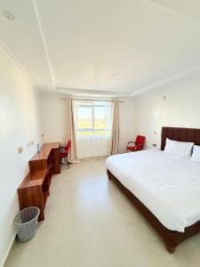 a bedroom with a bed and a desk and a window at Sacred Crown Suites in Naivasha