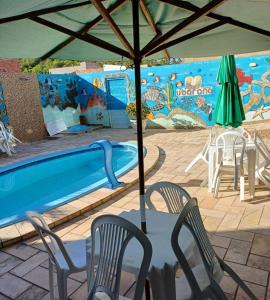 a table and chairs under an umbrella next to a swimming pool at Flat Ubarana Maragogi-AL in Maragogi