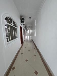 an empty hallway with white walls and a window and a tile floor at Hotel Victoria in Nueva Loja