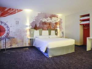 a bedroom with a large bed with a painting on the wall at ibis Styles Poitiers Centre in Poitiers +77 photos