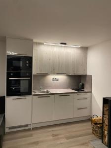 a kitchen with white cabinets and a sink and a microwave at Apartmány Krymlov in Oleška