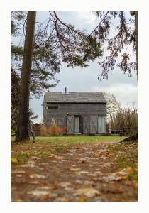 an old barn with a tree in the foreground at Brīvdienu Māja Martz in Engure