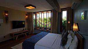 a bedroom with a bed and a tv and windows at Vila das Águas in Atins