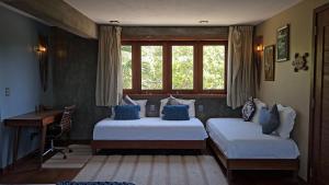 a bedroom with two beds and a desk and a window at Vila das Águas in Atins