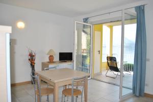 uma sala de jantar com mesa e cadeiras e uma varanda em Residence White Beach em Lierna
