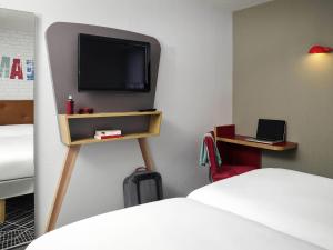 a room with a bed and a tv on a wall at ibis Styles Chartres Métropole in Chartres