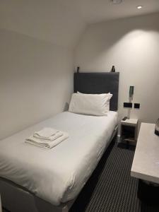 a bedroom with a white bed with two towels on it at Lidos Hotel in London