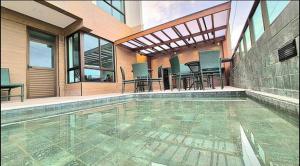 a swimming pool with chairs and tables in a house at Estrela Do Mar flat Beach in Porto De Galinhas