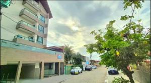 a building with cars parked on the side of a street at Estrela Do Mar flat Beach in Porto De Galinhas