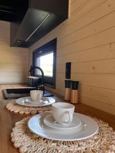 two cups and plates on a table in a kitchen at Tiny House Barujec in Brenna