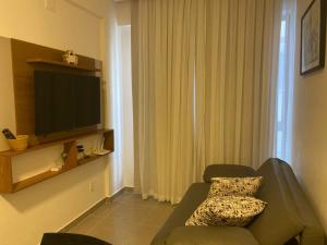 a living room with a couch and a flat screen tv at Estrela Do Mar flat Beach in Porto De Galinhas
